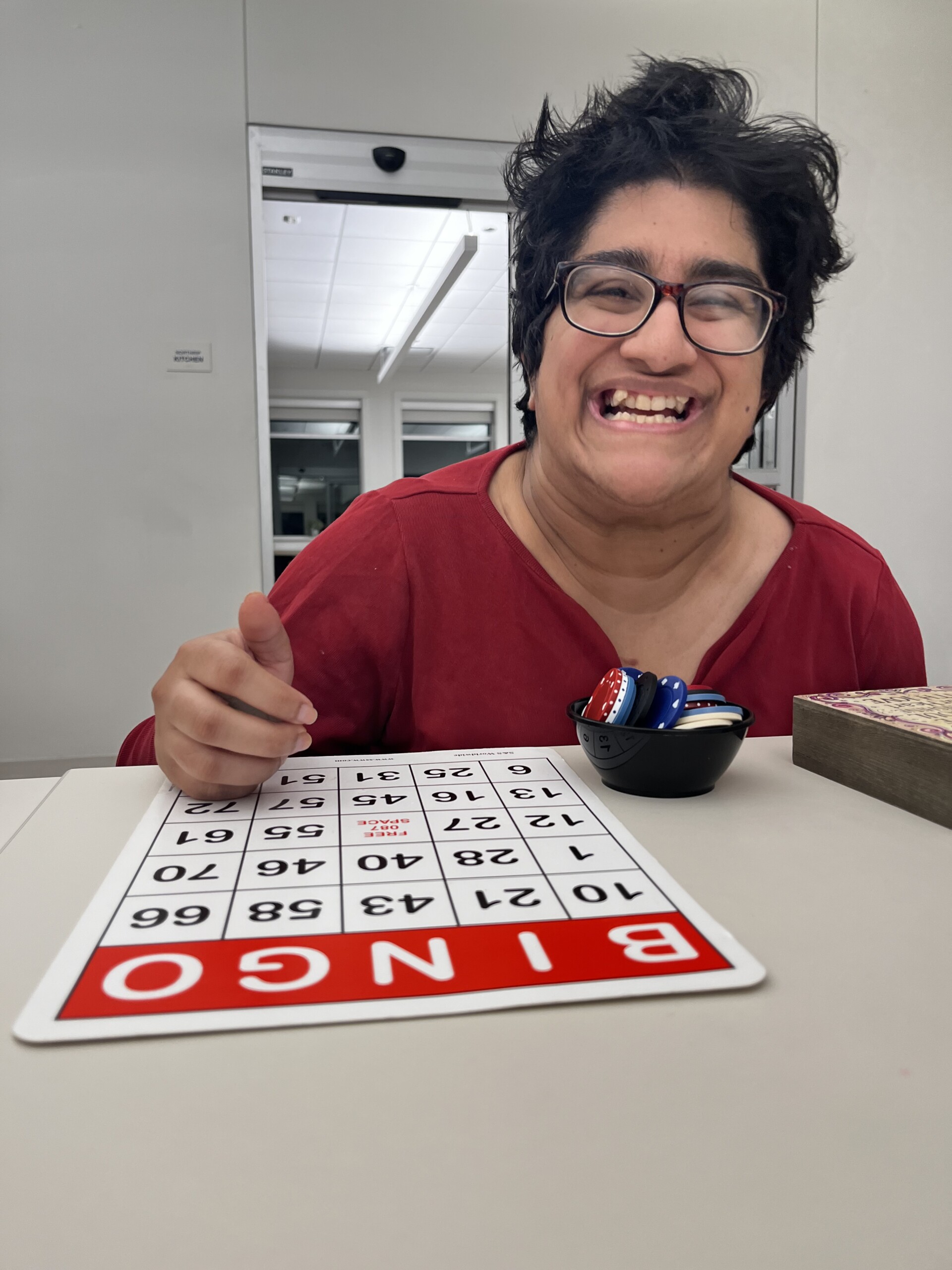 A cel member smiling while playing bingo during Wednesday Night Sampler.