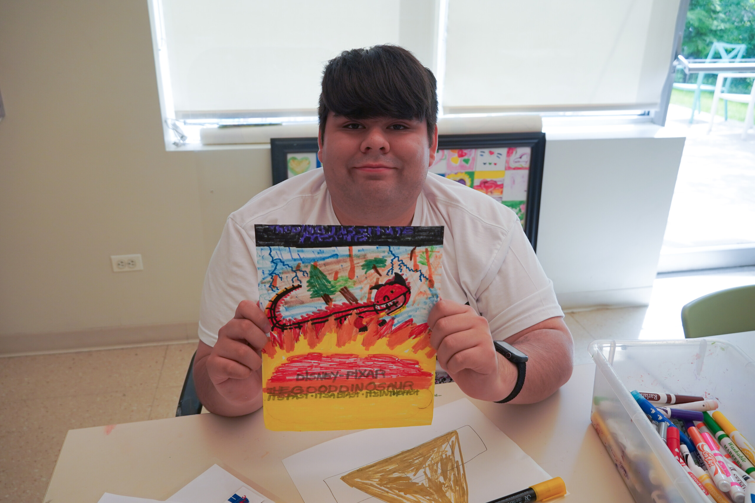 A photo of a CEL REACH member proudly showing artwork created during program.