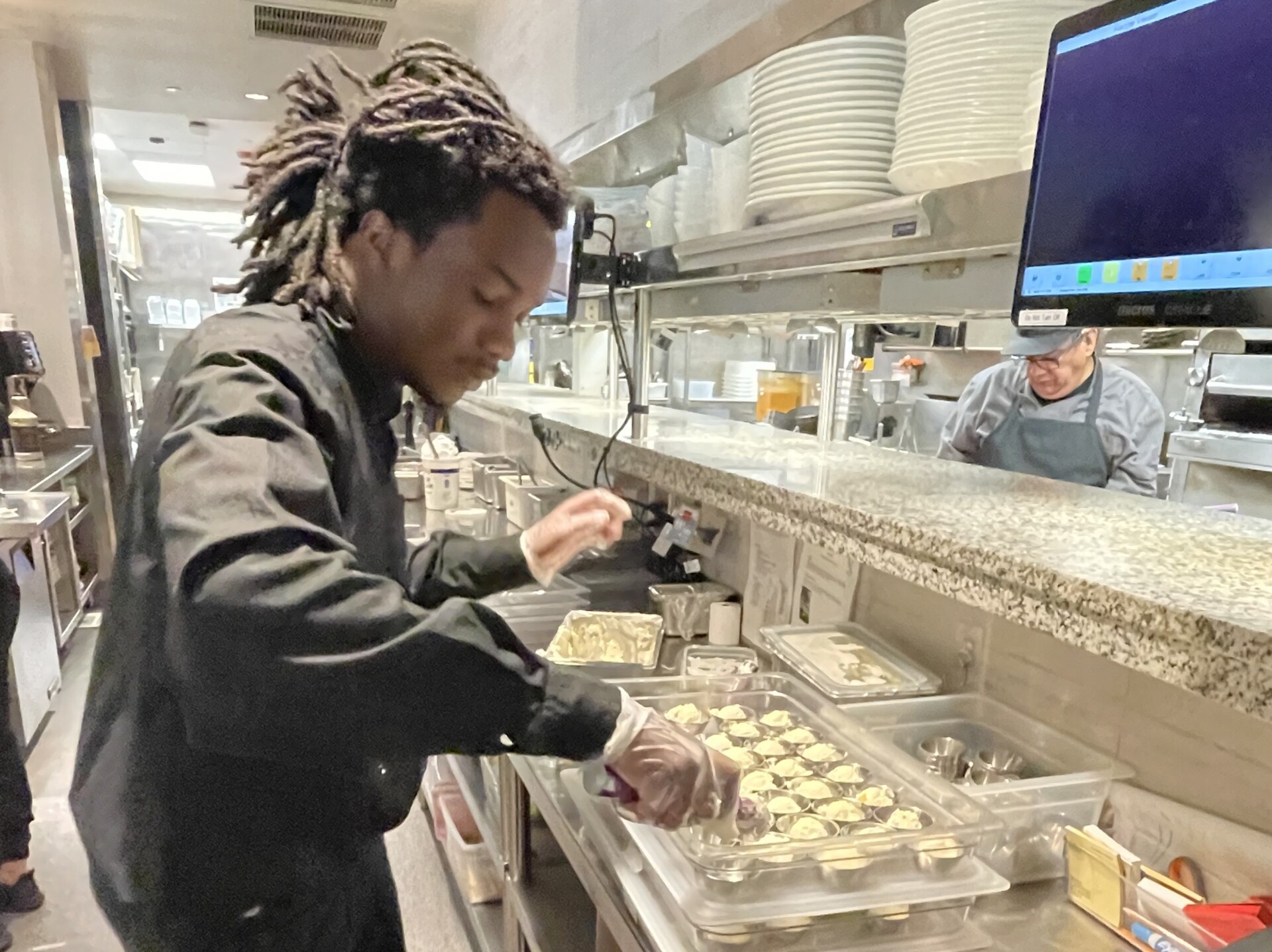 A photo of employment member Sheerba A. at Cooper's Hawk Restaurant and Winery working his first job as server assistant.