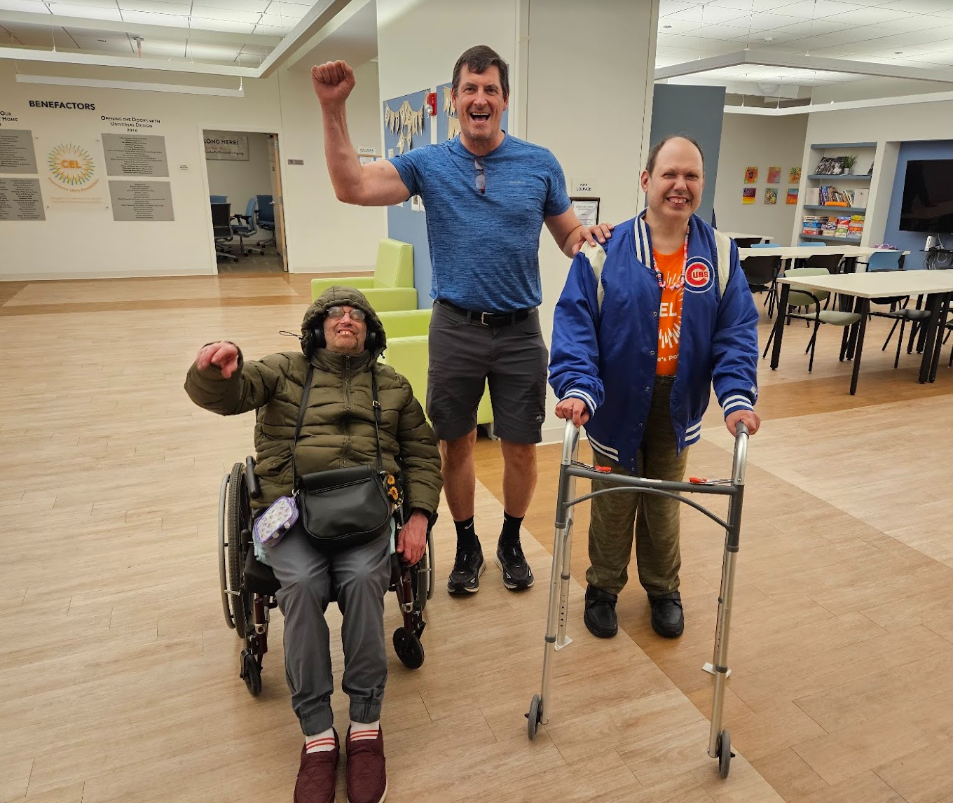 A group of CEL members with volunteer smiling and waving during guy's night.