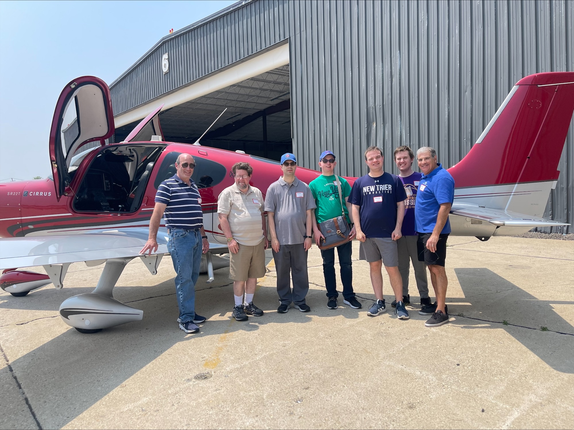 A group of CEL members posing with volunteers outside an aircraft.