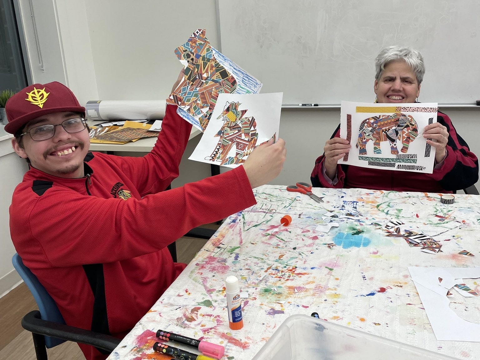 A picture of two CEL members during Tuesday art night proudly showing off their artwork.