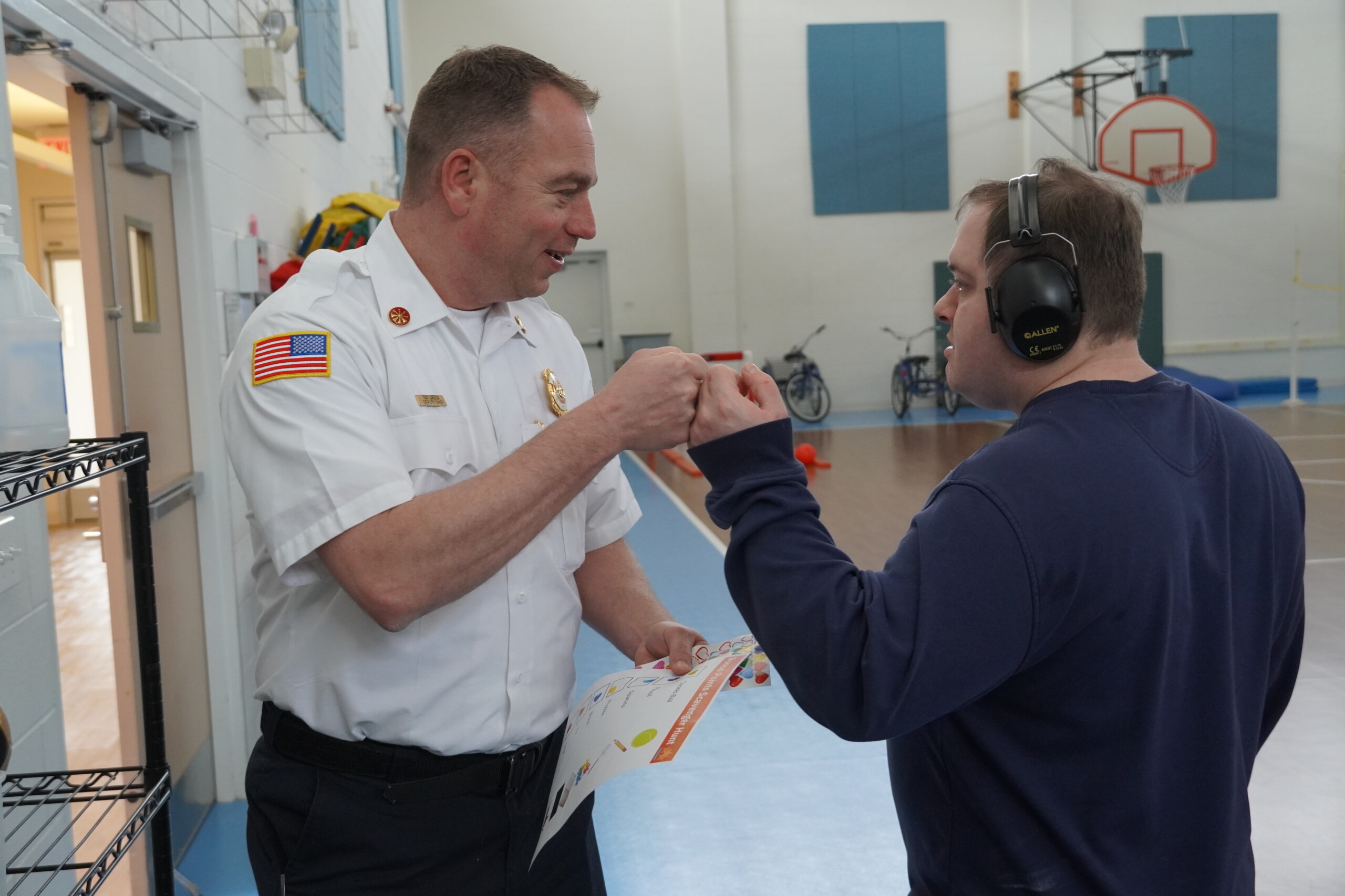 A picture of a CEL member with a first responder fist bumping during activity in gym.