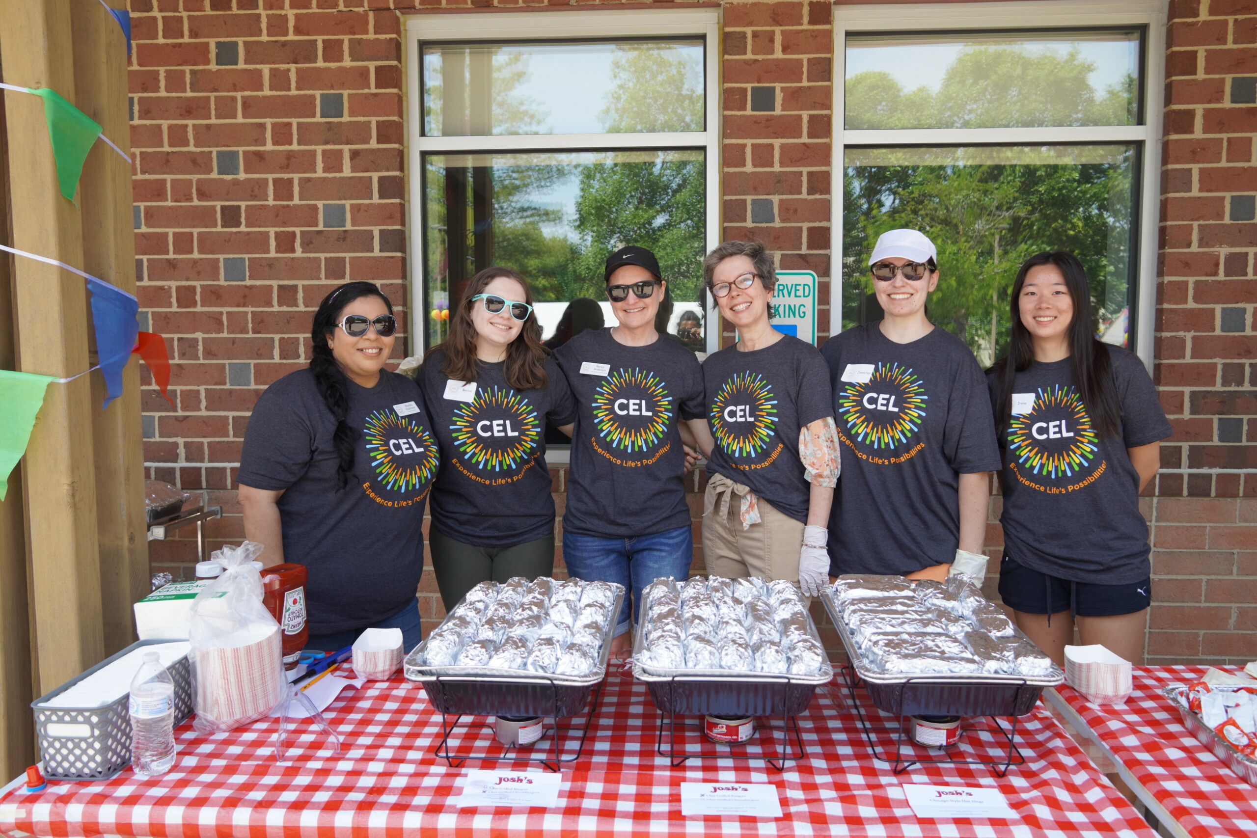 Group of CEL staff and volunteer smiling while wearing matching CEL shirts during a community day event