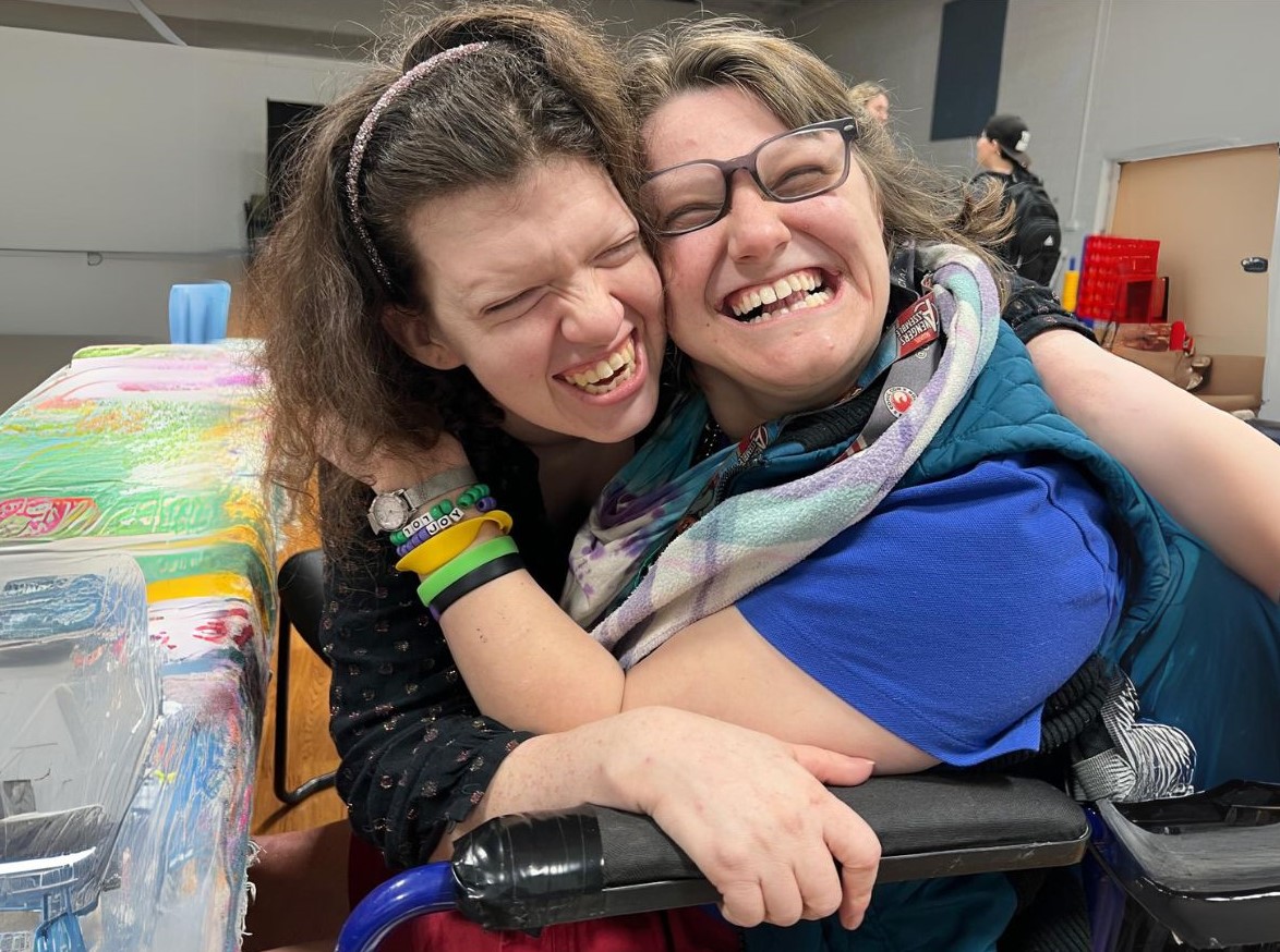 A CEL member hugging and smiling with her friend in the CEL gym.