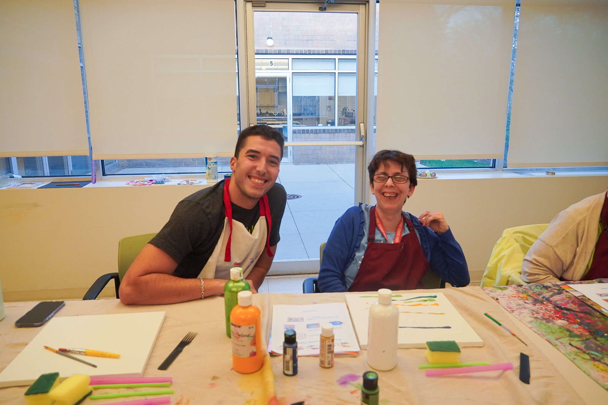 A photo of young leadership committee member doing art with CEL member.