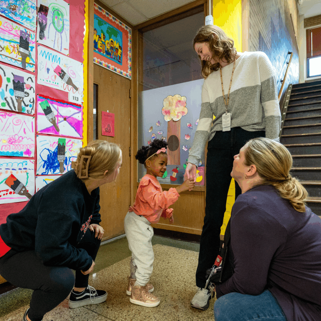 three educators talk with a young student in a school hallway