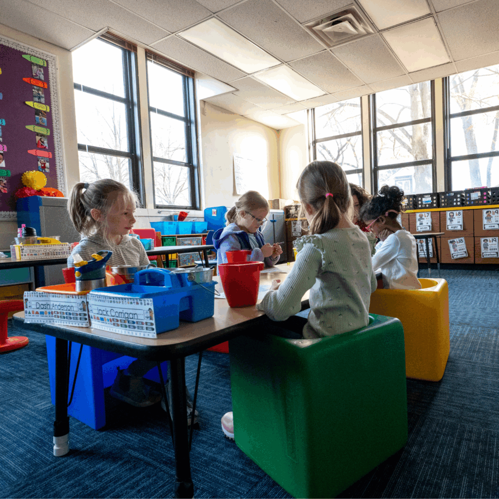Students at a classroom table with colorful chairs