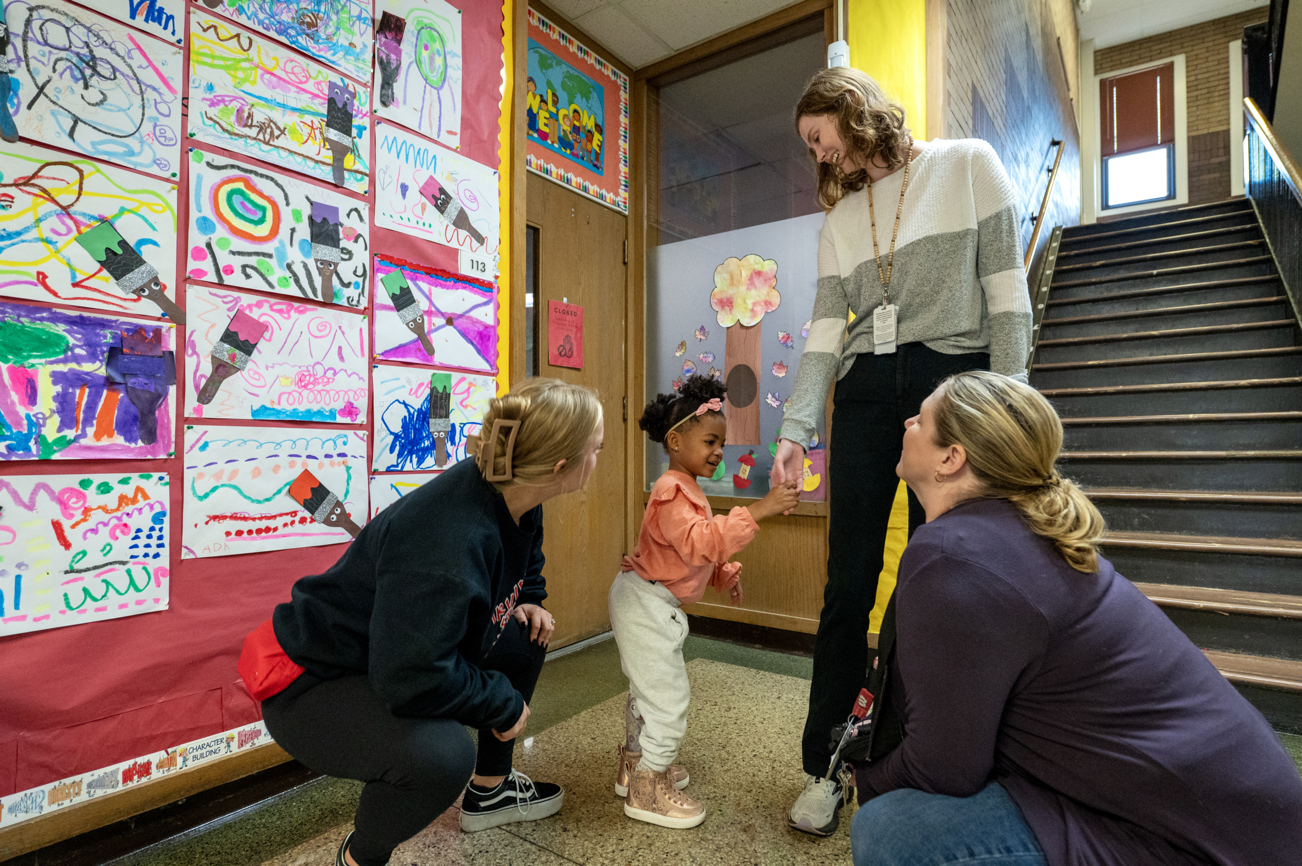 Educators talking with young student in hallway
