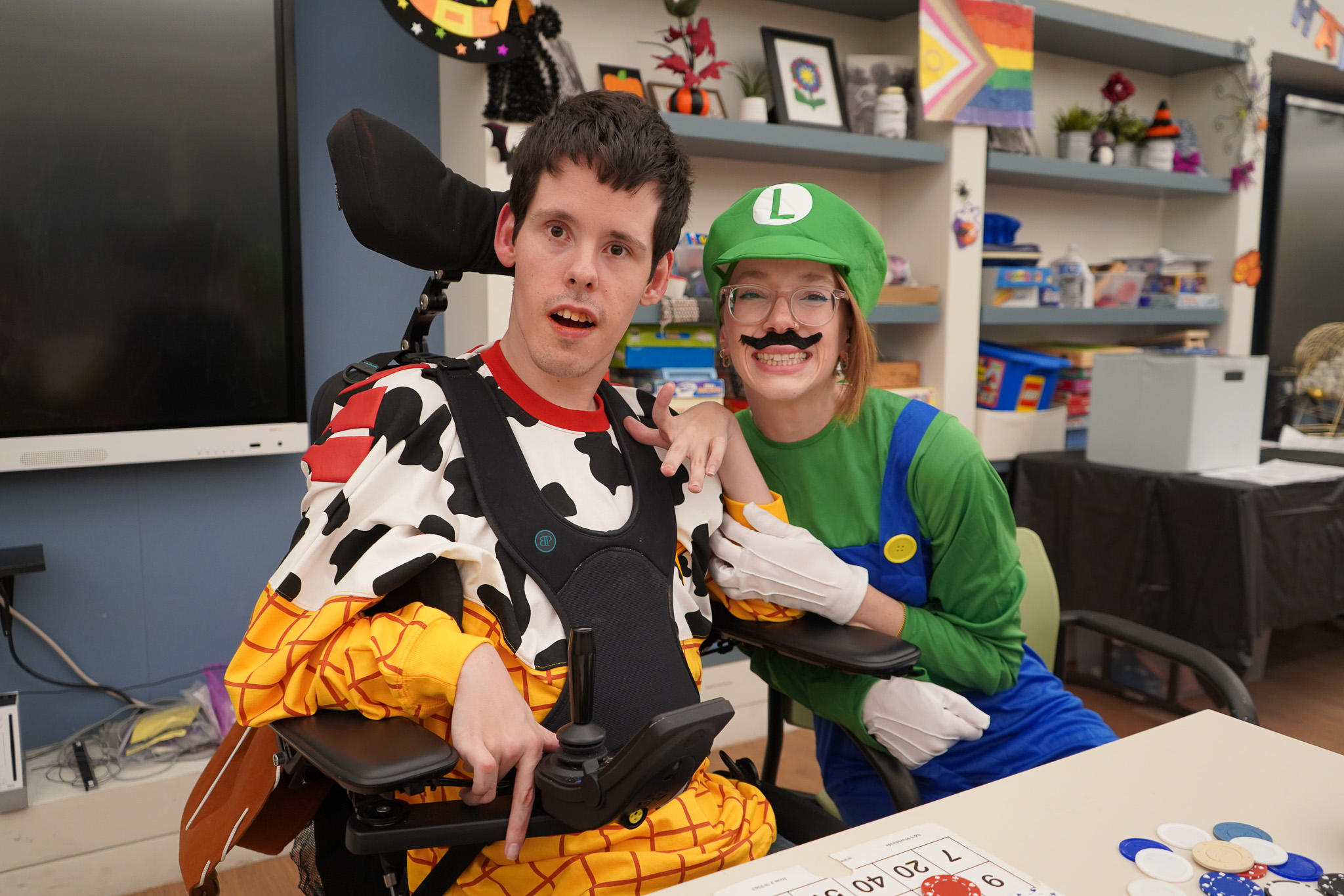 A CEL Member in a Toy Story Woody costume and a staff member in a Luigi costume play bingo at the Harvest Dance