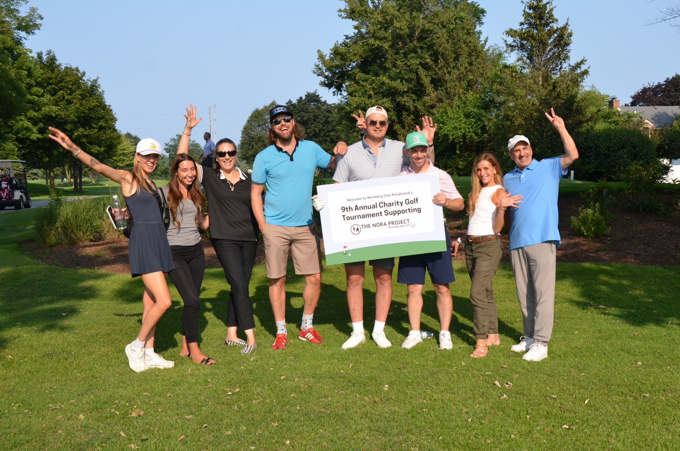 Weinberg Choi golf outing attendees posing with sign