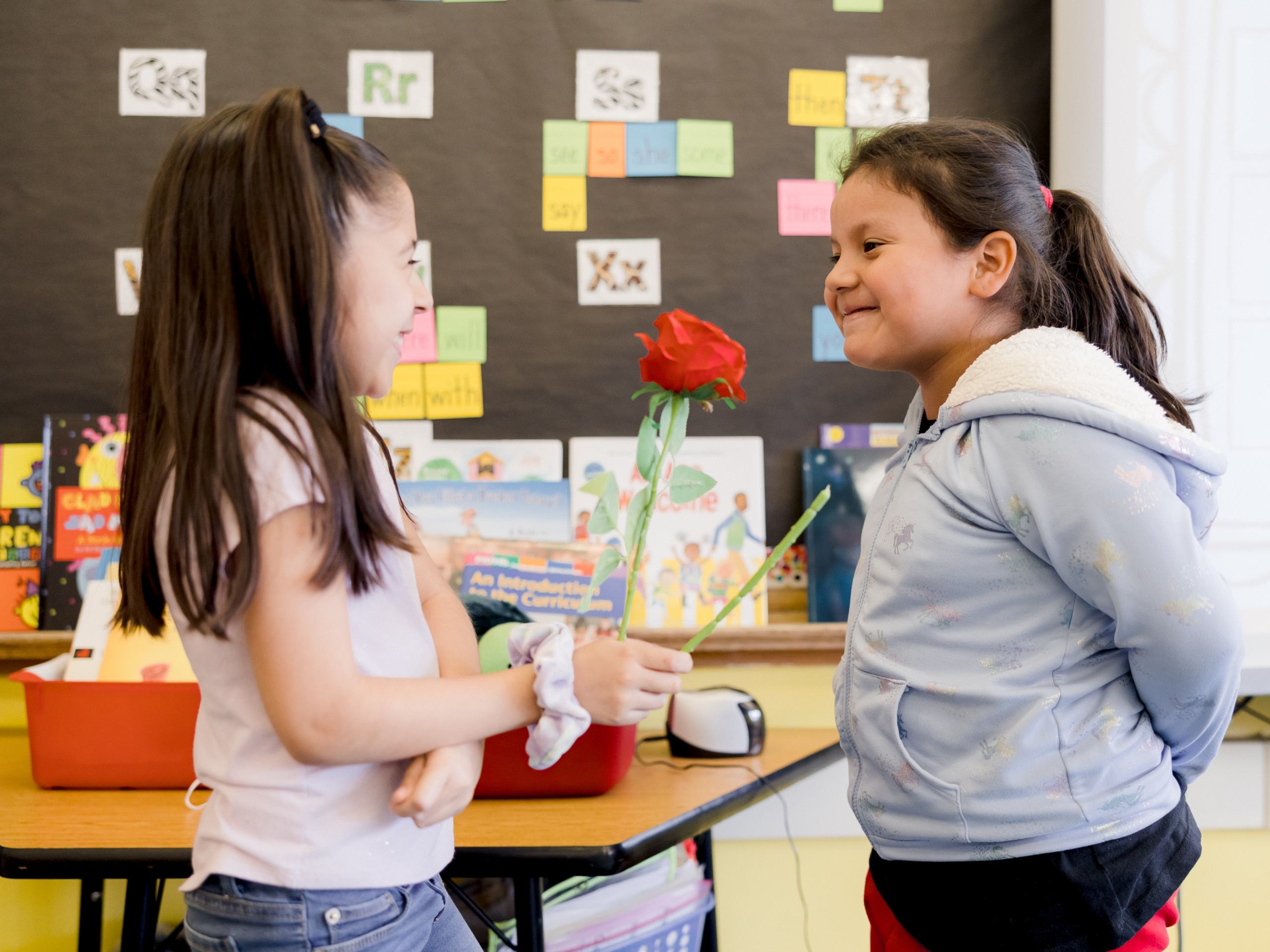 young student gives flower to another