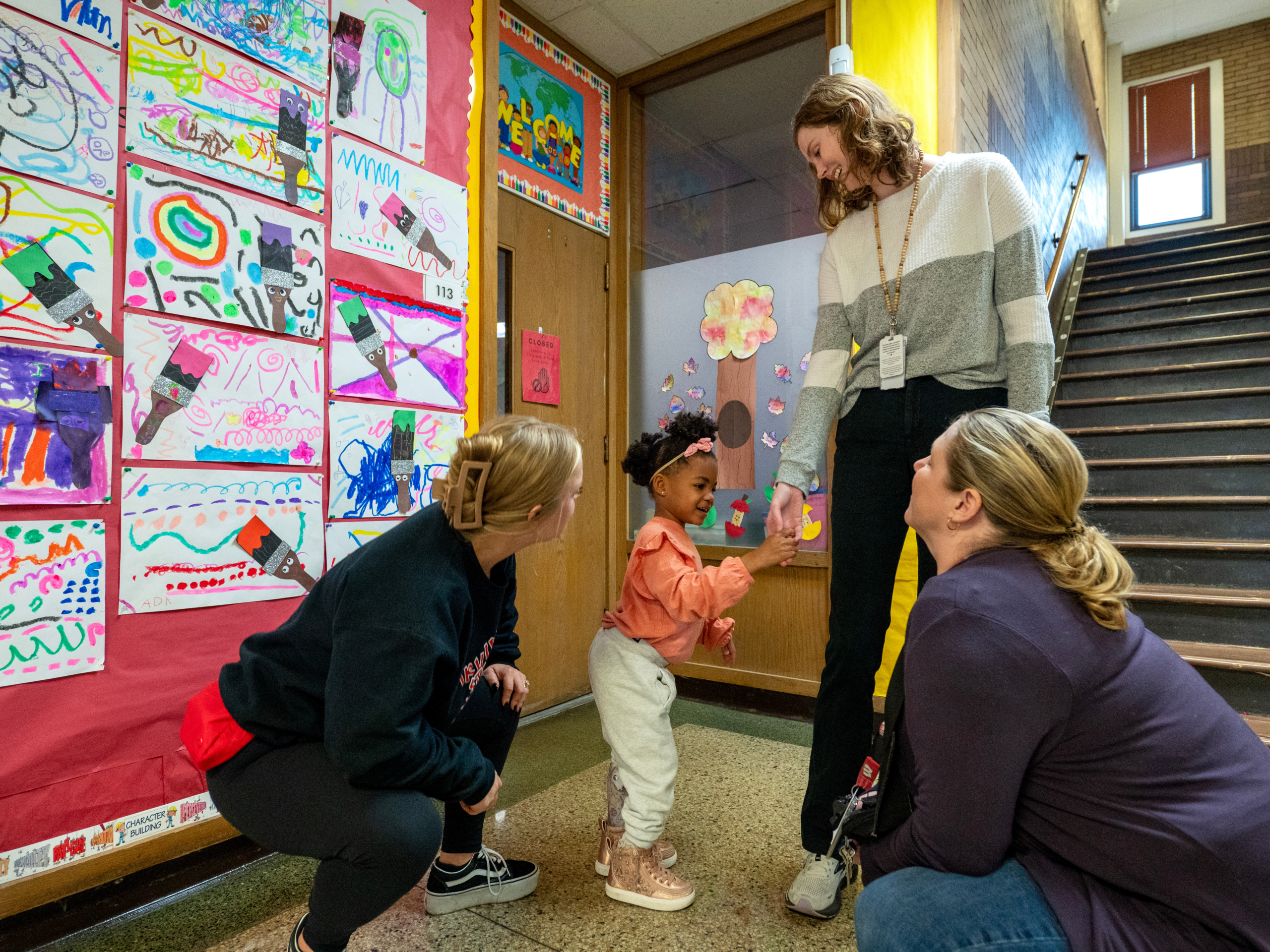 three educators and a young girl in a school hallway