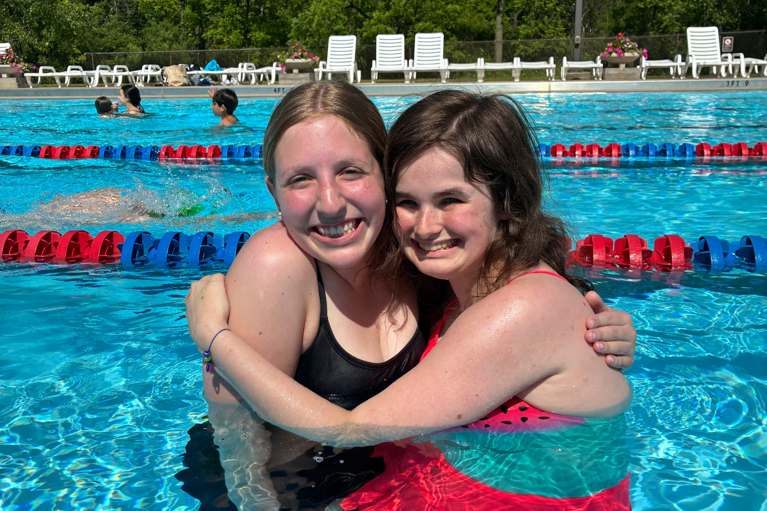 Summer Camp member and counselor hug in pool